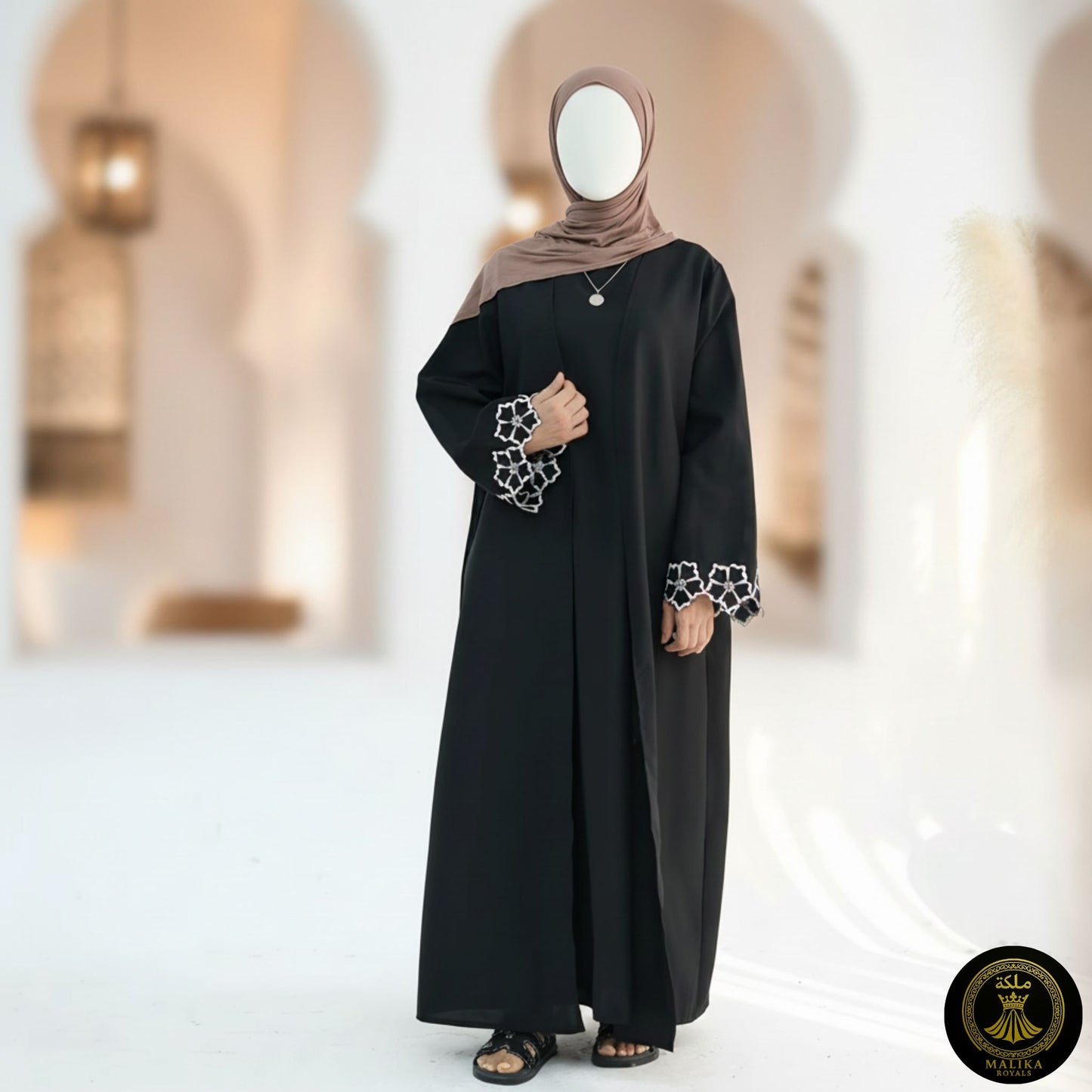 Woman wearing a black abaya with star patterns on the sleeves in an indoor setting.