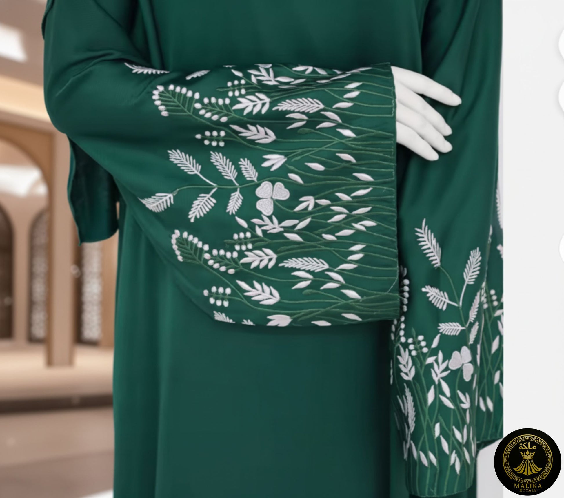 Green dress with white floral patterns held by a hand against a middle eastern architectural background